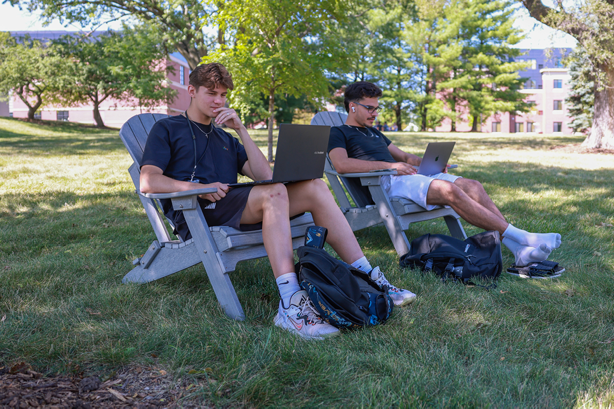 Grand View students studying together in lawn chairs outside near our residence halls on their laptops